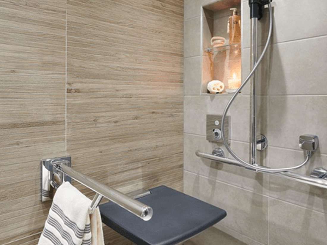 A level-access wet room with a fold-down shower seat and grab rail